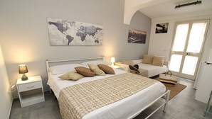A bedroom with a large bed, two bedside tables, a world map on the wall, and a door with a view. - SUMMER ROOM (Siniscola)