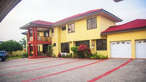 A two-story building with a red roof, a covered entrance, and a paved driveway. - Eey Kay Booking Ghana (Accra)