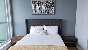 A modern bedroom with a large bed, a chandelier, a zebra artwork, and a window. - Beautiful Condo with spectacular views + 1 Parking in Mississauga Downtown (Mississauga)