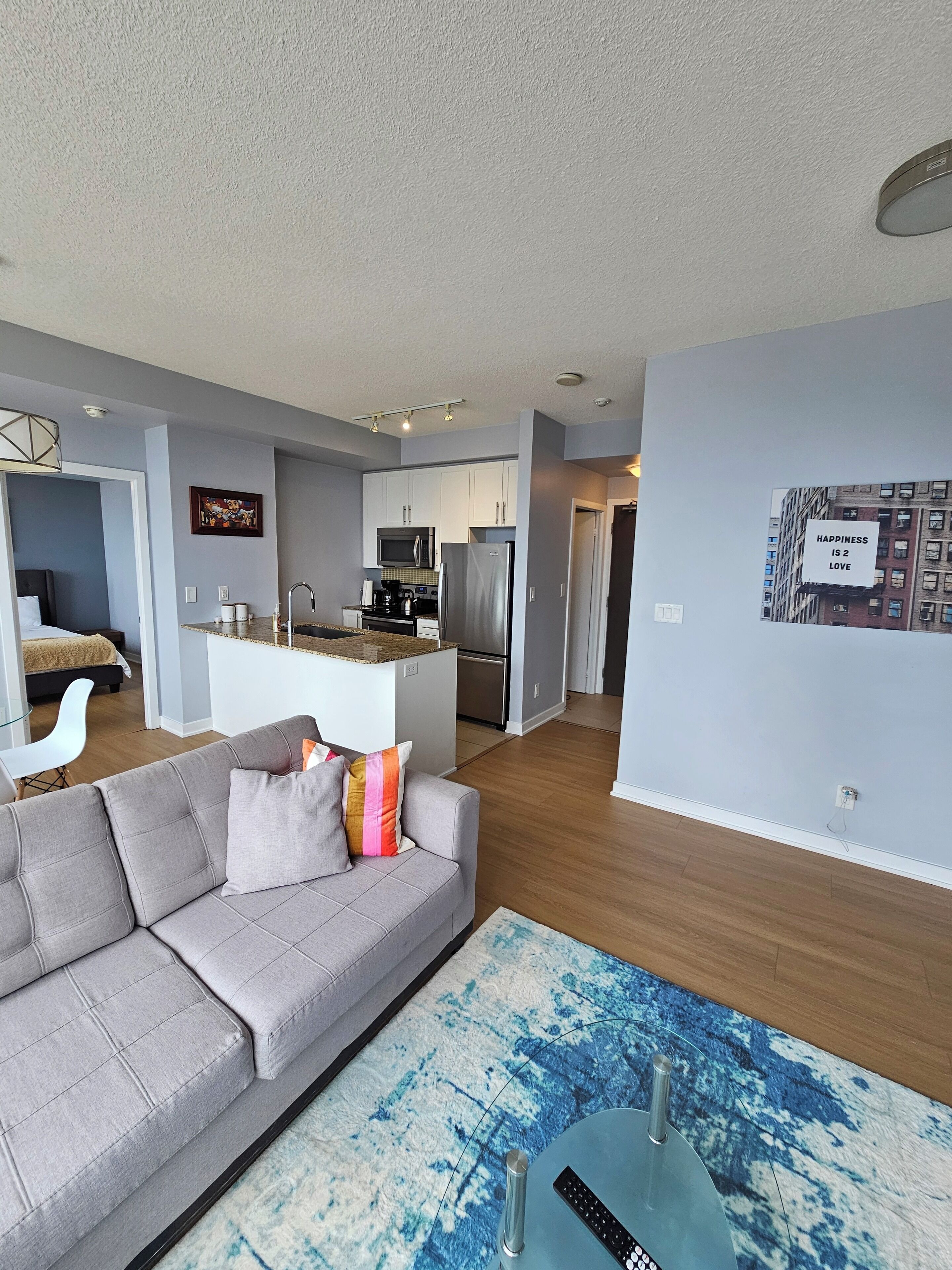 A modern living room with a grey sofa, a coffee table, and a kitchen area in the background.