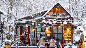 A rustic cabin-style building with a wooden exterior, surrounded by snow-covered trees.