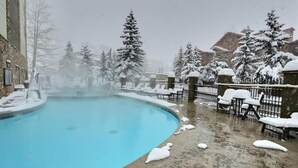 A swimming pool with snow-covered surroundings and a stone building in the background.