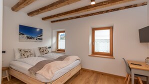 A bedroom with a wooden bed, a desk, and a window with a view of mountains. - Ciesa dela Maestra 2ªB (Rocca Pietore)