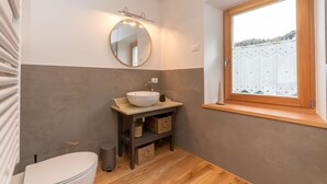 A bathroom with a round mirror, a sink, and a window. - Ciesa dela Maestra 2ªB (Rocca Pietore)
