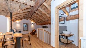 Un intérieur en bois comprenant un coin repas, une cuisine dotée d’un plan de travail en bois et un escalier apparent.