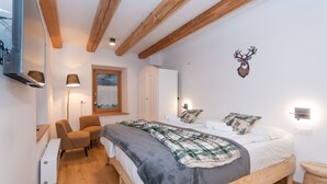 Une chambre à coucher comprenant un lit, deux chaises, une armoire, un radiateur et une lampe fixée au mur.