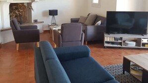 Una sala de estar con un sofá, sillones, televisión y chimenea.