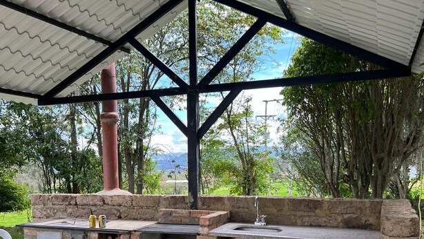An outdoor barbecue area with a stone oven, a sink, and a covered seating area. - Escape to paradise in Paipa, Boyacá in this beautiful Casa Rural San Cipriano!🏡 (Paipa)