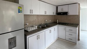 A modern kitchen with white cabinets, a stainless steel refrigerator, a granite countertop, and a built-in oven. - Escape to paradise in Paipa, Boyacá in this beautiful Casa Rural San Cipriano!🏡 (Paipa)