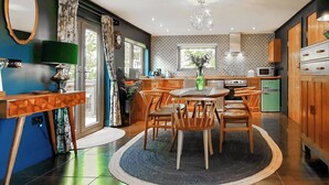 Une cuisine moderne avec un coin repas, des meubles en bois, un réfrigérateur vert et un lustre.