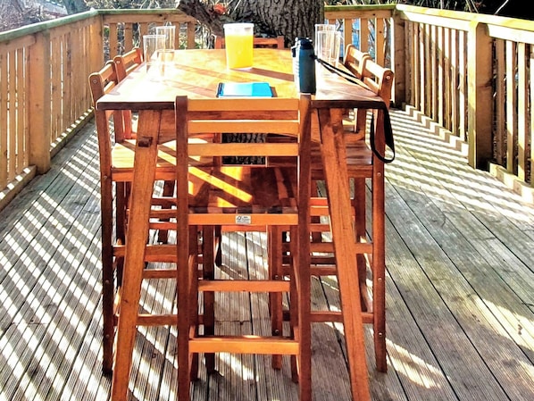 A wooden deck with a table and chairs, a blue water bottle, and a glass of orange juice.