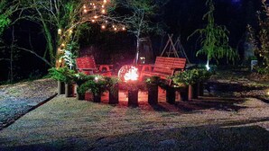Un espace extérieur aménagé pour les soirées, avec des guirlandes lumineuses, des bancs en bois et une petite table.