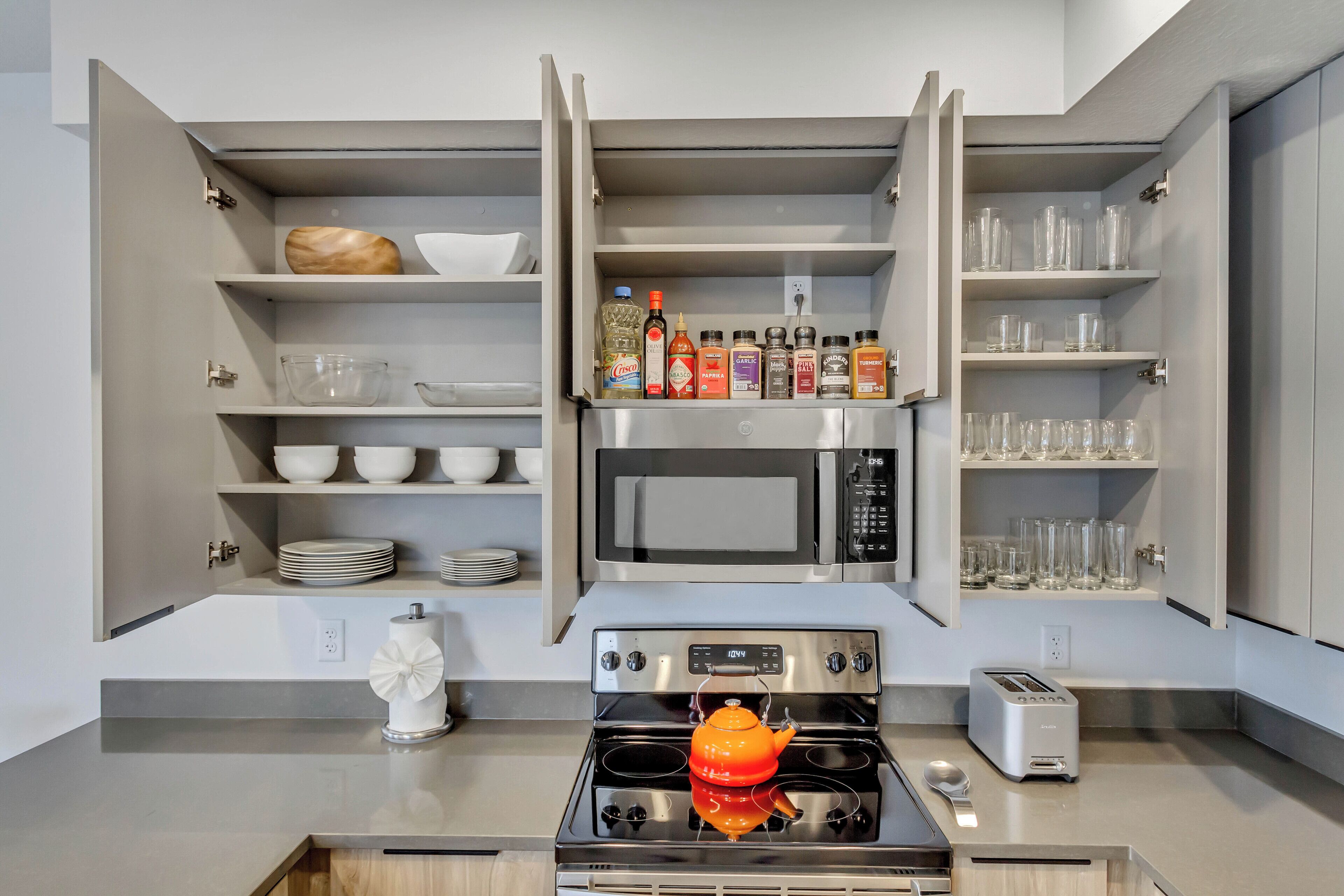 Una cocina moderna con armarios abiertos, un microondas, una estufa y un tostador.