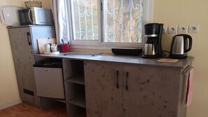 Una cocina compacta equipada con lavavajillas, microondas, cafetera y hervidor.