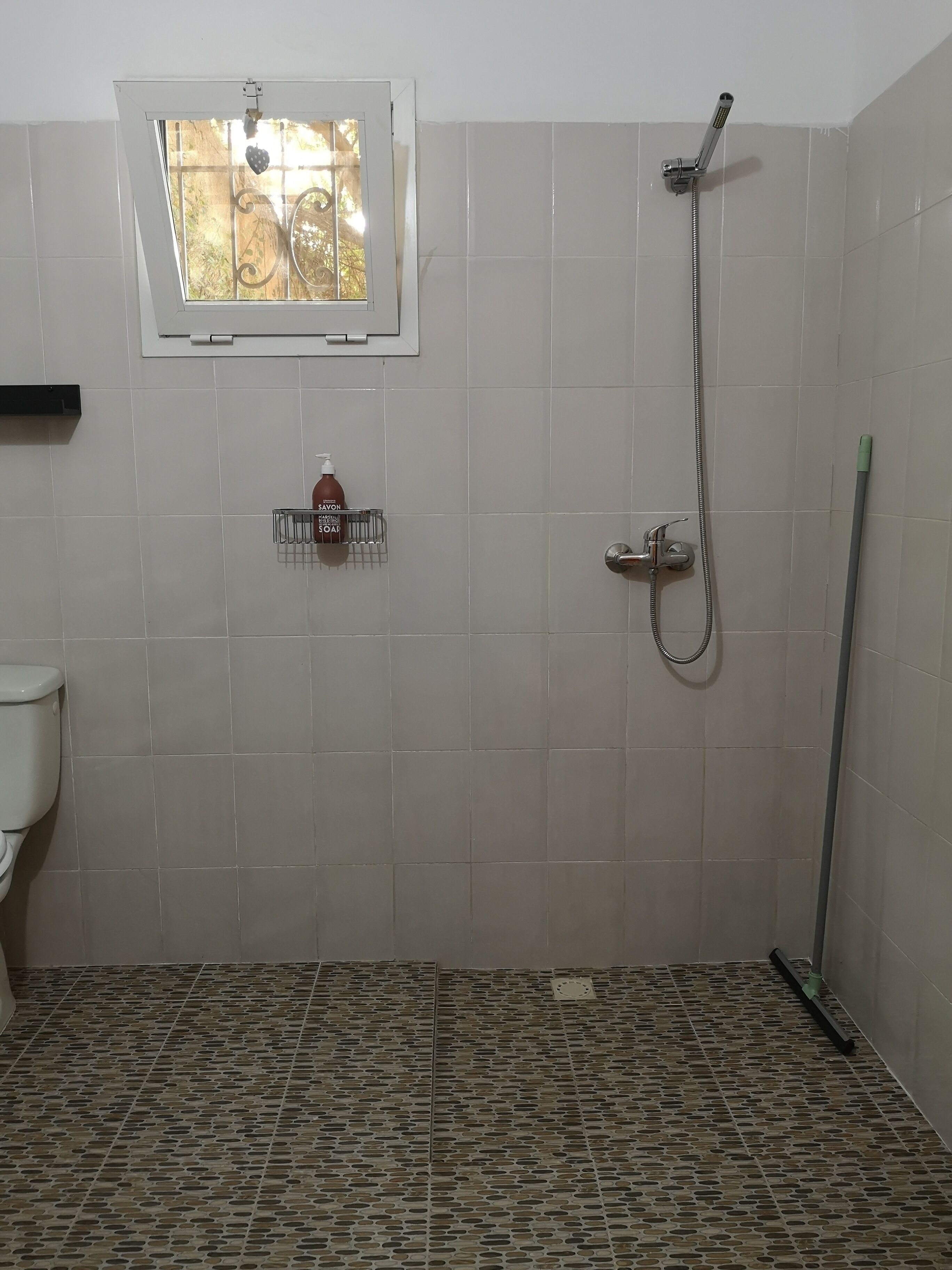 Un bany amb dutxa, vàter i finestra amb vistes.