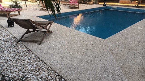 Una piscina con una tumbona y una silla con estampado rosa y blanco.