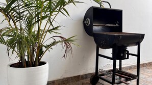 Een potplant naast een draagbare grill op een betegelde vloer.