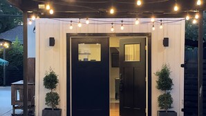 A modern building with a black door, a small window, and a porch area with string lights. - Curtis Park Charmer! (Sacramento)