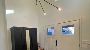 A room with wooden flooring, a black wardrobe, a white door with a window, and a ceiling light fixture. - Curtis Park Charmer! (Sacramento)