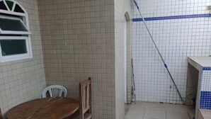 Un petit coin cuisine avec un mur recouvert de carreaux, une table en bois avec des chaises et une fenêtre à carreaux.