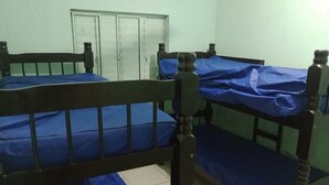 Une chambre avec des lits superposés, une armoire et un sol carrelé.