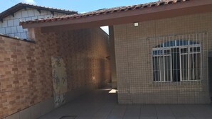 Un espace extérieur abrité, doté d’un sol carrelé, d’un mur en briques et d’une fenêtre avec des barreaux en métal.
