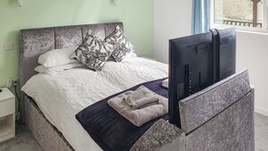 A bed with a grey headboard, white bedding, and a black and white patterned pillow. A flat-screen TV is mounted on the headboard. - Classroom One - UK48650 (Lifton)