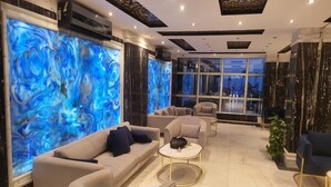 Un área de descanso moderna con un amplio mural azul abstracto, asientos cómodos y vistas a través de grandes ventanales.