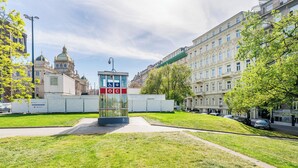 A building with classical architecture, a central glass structure, and a well-maintained lawn.