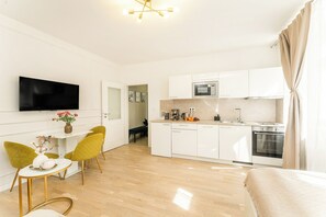 Una cucina moderna con mobili bianchi, un forno a microonde e un forno. C'è un'area pranzo con un tavolo e sedie.