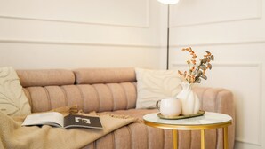 A cozy room with a sofa, a small round table with a white vase and a cup, and a floor lamp.