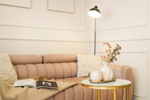 A cozy room with a sofa, a small round table with a white vase and a cup, and a floor lamp.