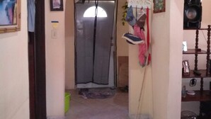 Un couloir avec un sol carrelé, une horloge au mur, une porte et un petit tapis.