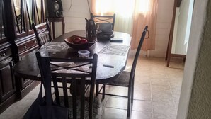 Un coin repas comprenant une table ronde, des chaises, un buffet et un haut-parleur.