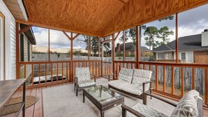 A covered outdoor patio with wicker furniture, a glass table, and a view of the neighborhood. - Sawgrass Cottage | 3BR with Deck (Columbia)