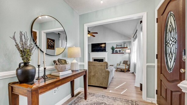 A hallway with a wooden console table, a mirror, a vase with plants, a rug, and a door with a decorative glass panel. - Sawgrass Cottage | 3BR with Deck (Columbia)