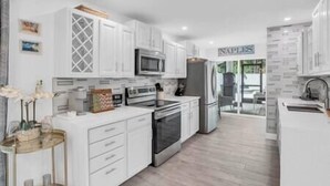 Une cuisine moderne avec des meubles blancs, des appareils en acier inoxydable et un plancher en bois.