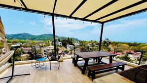 Une terrasse extérieure couverte, dotée d’un plancher en bois, d’une table, de chaises et d’un hamac.