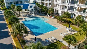 Um hotel com uma piscina grande, espreguiçadeiras e palmeiras.