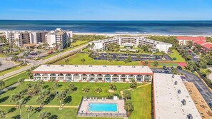 Vista aerea di un resort con piscina, diversi edifici e spiaggia.