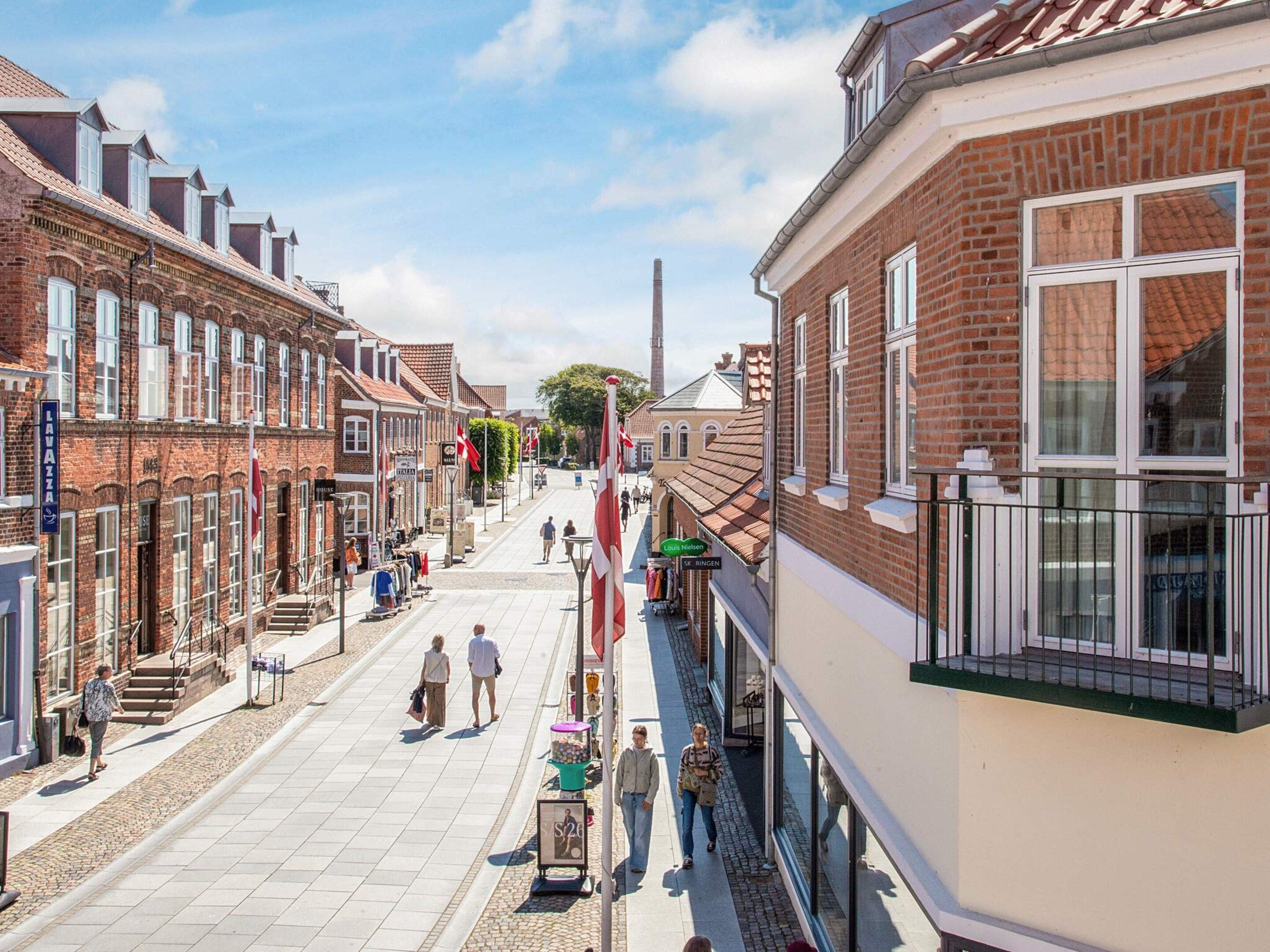 Una calle con edificios, una bandera y un letrero.