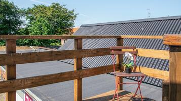 Una terraza de madera con una silla plegable roja y una planta en maceta.