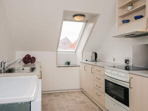A compact kitchen with a window, a sink, a kettle, and a stove. - 6 Person Holiday Home in Ringkobing (Ringkobing)