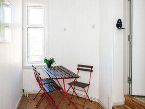 A room with a window, a table with chairs, a potted plant, and a door with a handle. - 6 Person Holiday Home in Ringkobing (Ringkobing)