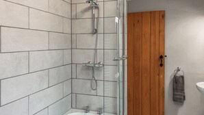 Ein Badezimmer mit Dusche, Badewanne und einer Holztür.