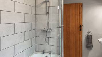 A bathroom with a shower, a bathtub, and a wooden door.