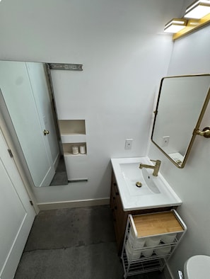 Ein kleines Badezimmer mit einem weißen Waschbecken, einem Spiegel und einer Toilette.