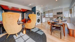 A modern kitchen with white cabinets, a microwave, and a sink. There is a dining area with a table and chairs. - Magical Stay Near Disneyland with Pool & Fire Pit (Santa Ana)
