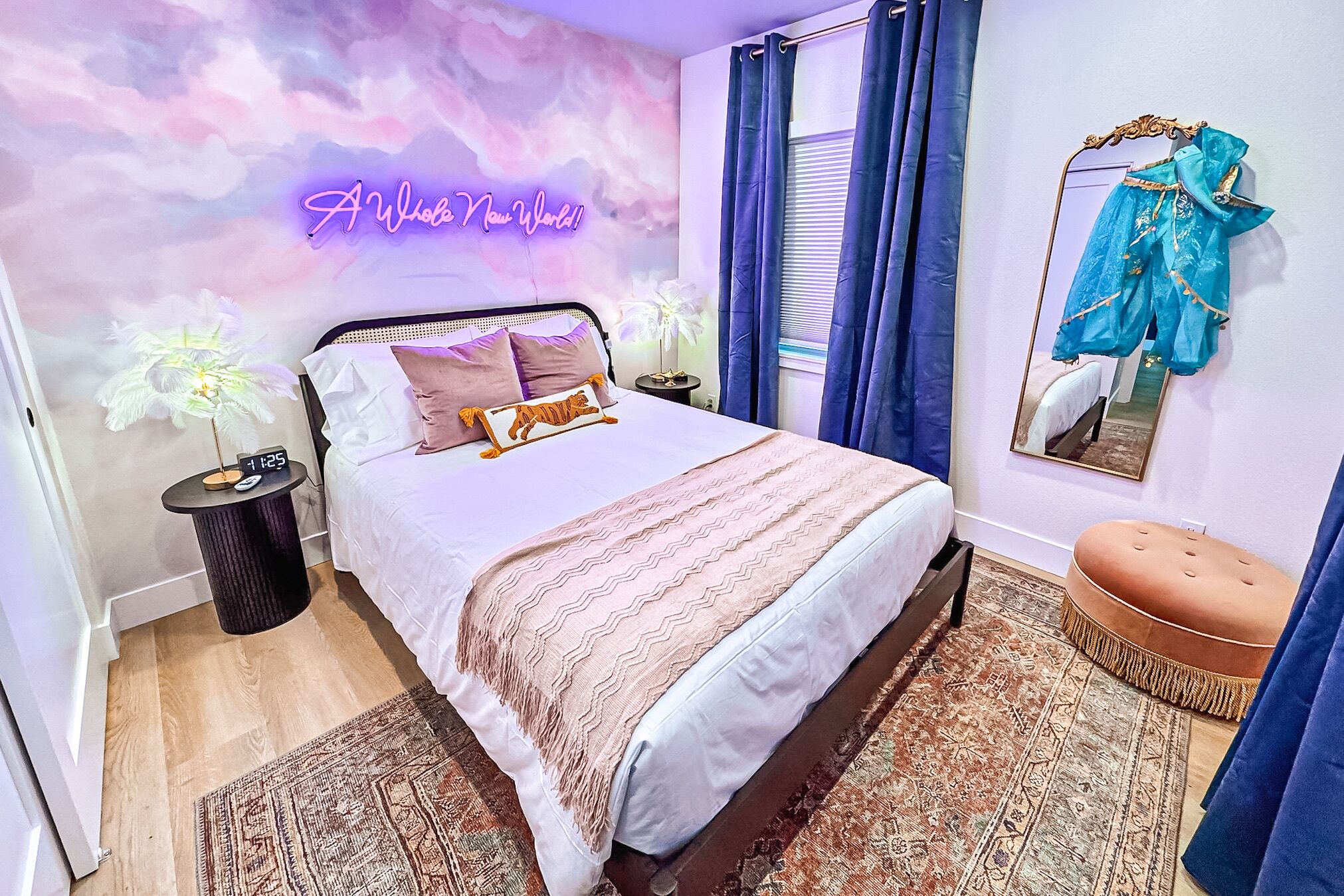 Une chambre à coucher avec un lit, une table de chevet, un miroir, un rideau bleu, un néon et une décoration florale.
