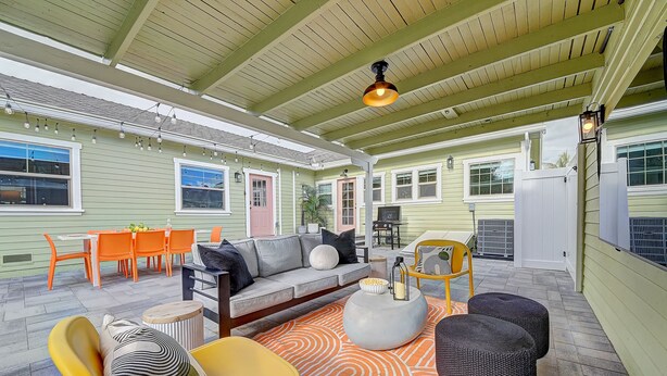 A covered patio area with a sofa, chairs, and a dining table. - Magical Stay Near Disneyland with Pool & Fire Pit (Santa Ana)